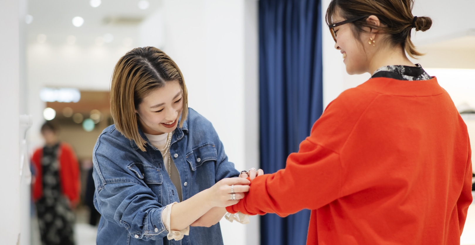 お客さんが試着した服の袖の長さを調整する女性